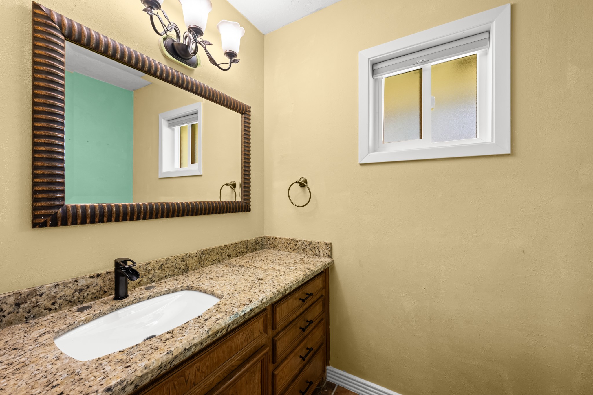 616 Cannan Drive Angleton, TX 77515 - Photo 19 of 49 Conveniently located for guests, this updated powder room features a granite-topped vanity, stylish framed mirror, and modern fixtures. The functional layout and tasteful finishes provide both comfort and convenience for everyday use.
