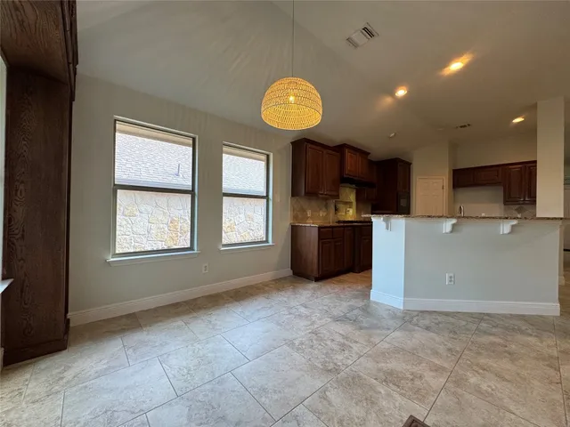 a view of an empty room with a window and kitchen area