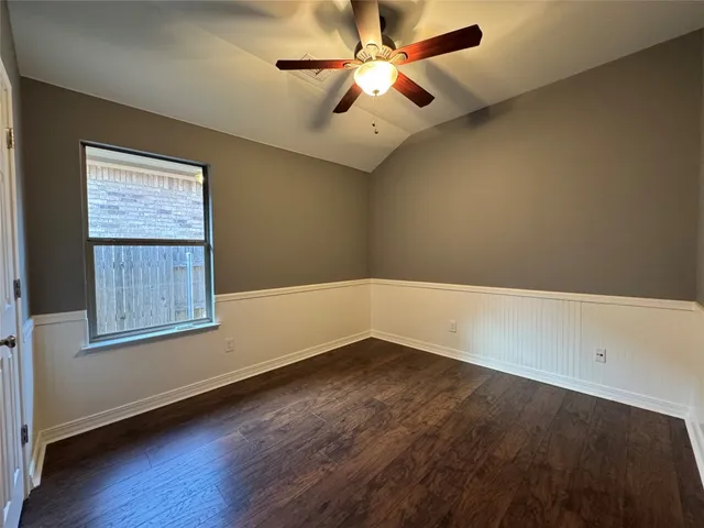 an empty room with wooden floor fan and windows