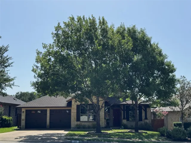 a backyard of a house with large trees and wooden fence