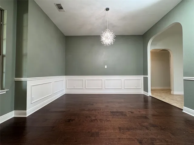 an empty room with wooden floor and chandelier