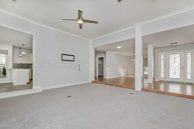 a view of an empty room with window and a kitchen
