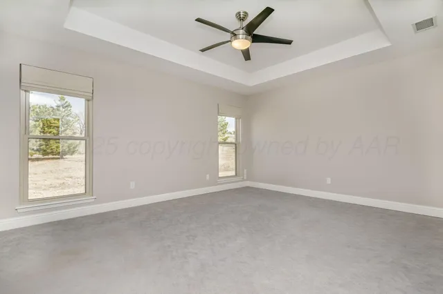 an empty room with windows and ceiling fan