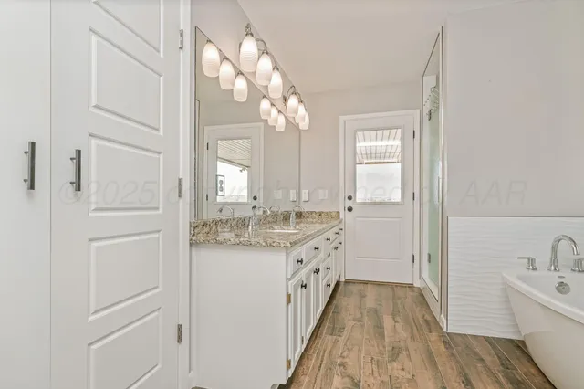 a bathroom with a granite countertop sink a toilet a mirror and bathtub
