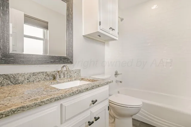 a bathroom with a granite countertop sink a toilet and bathtub