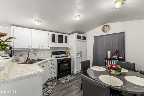 a kitchen with stainless steel appliances granite countertop a sink a stove a refrigerator a dining table and chairs with wooden floor