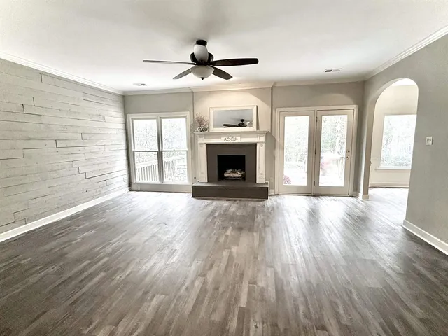 a view of an empty room with wooden floor fireplace and a window