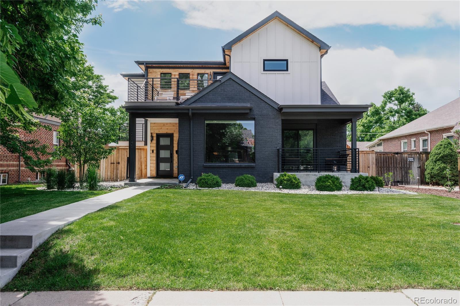 a view of a brick house with a big yard and large trees