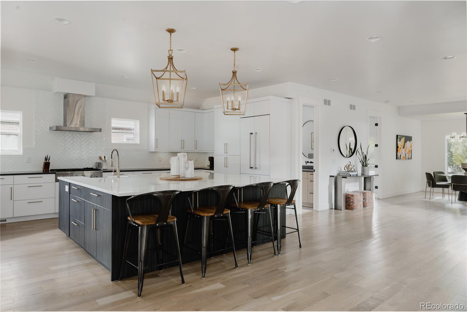 2645 Eudora Street Denver, CO 80207 - Photo 11 of 40 a kitchen with stainless steel appliances granite countertop a stove a sink dishwasher and white cabinets with wooden floor