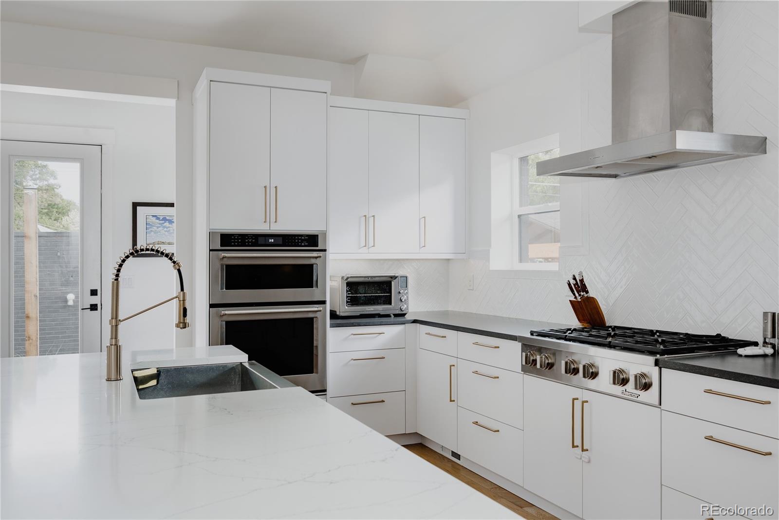 2645 Eudora Street Denver, CO 80207 - Photo 9 of 40 a kitchen with white cabinets and appliances