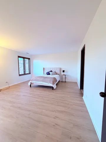a spacious bedroom with a bed and wooden floor