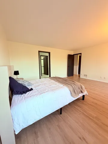a bedroom with a bed and wooden floor