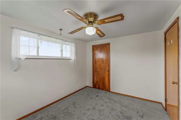 an empty room with a ceiling fan and a window