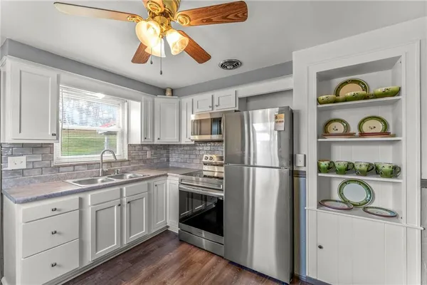 a kitchen with a refrigerator a sink and wooden floor