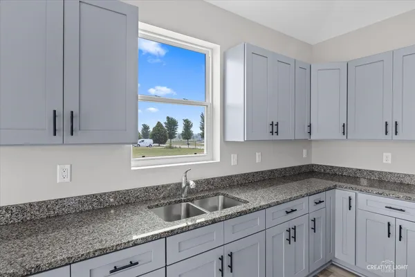 a kitchen with granite countertop a sink and cabinets