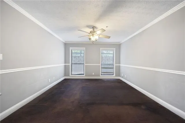 an empty room with windows and ceiling fan