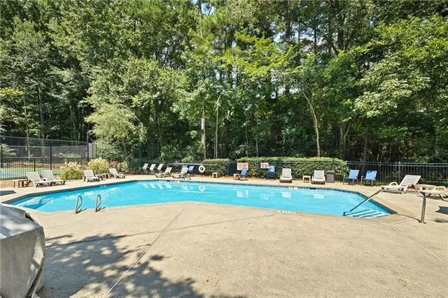a view of yard with swimming pool and trees in the background