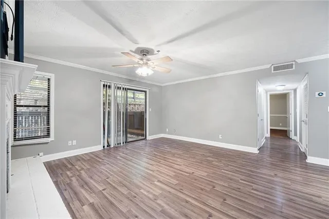 a view of an empty room with window and wooden floor