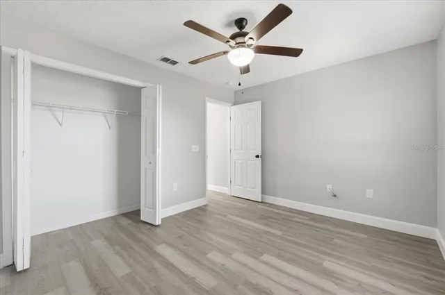 an empty room with wooden floor and ceiling fan