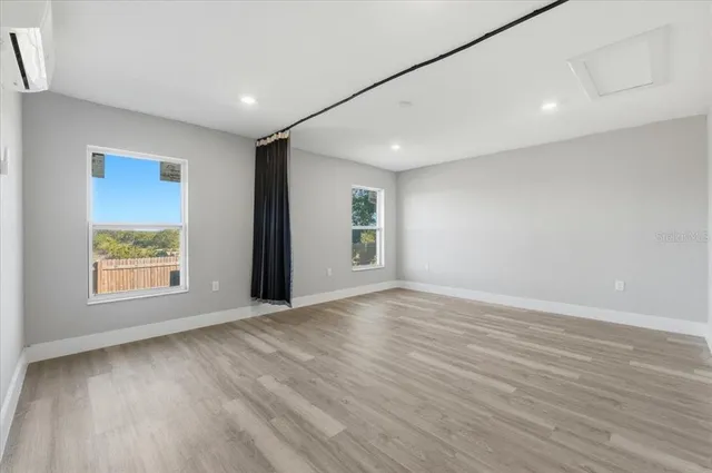an empty room with wooden floor and windows