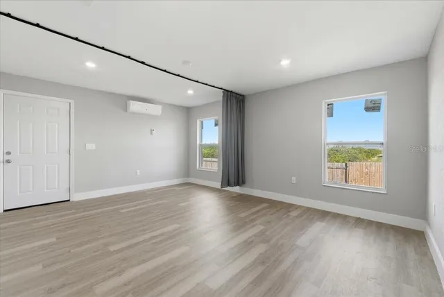 an empty room with wooden floor and windows