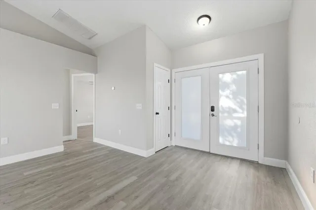 an empty room with wooden floor and windows