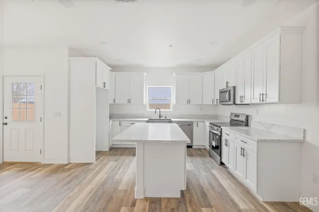 a kitchen with a sink a stove cabinets and wooden floor