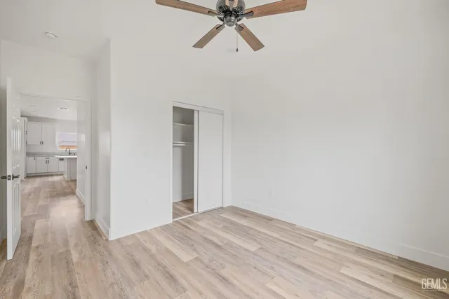 a view of a hallway with wooden floor and a ceiling fan
