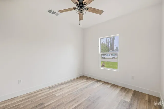 an empty room with a window and a ceiling fan
