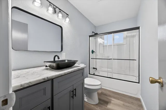 a bathroom with a granite countertop sink a toilet and mirror