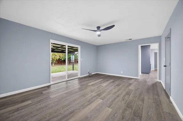 a view of an empty room with wooden floor and a window