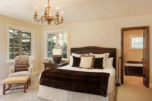 a bedroom with a bed a chandelier and a window