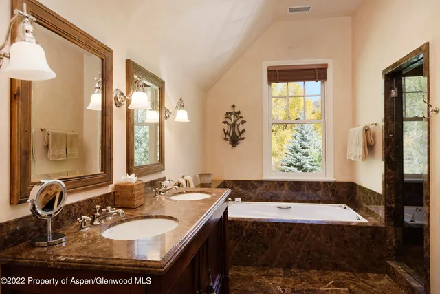 a bathroom with a granite countertop sink and a bathtub next to a window