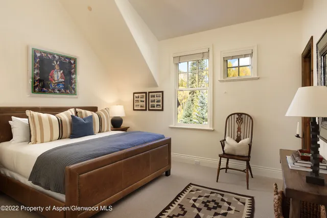a bedroom with a bed and a potted plant on the dresser