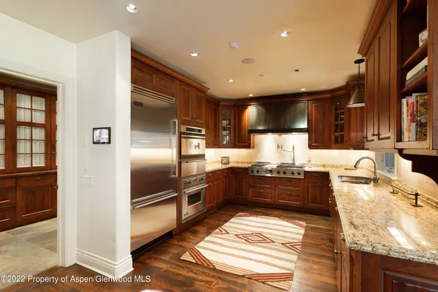 a large kitchen with granite countertop a large counter top stainless steel appliances and cabinets