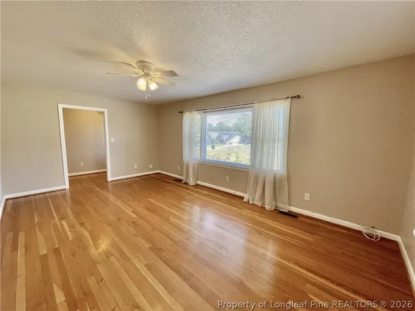 a view of empty room with wooden floor and fan