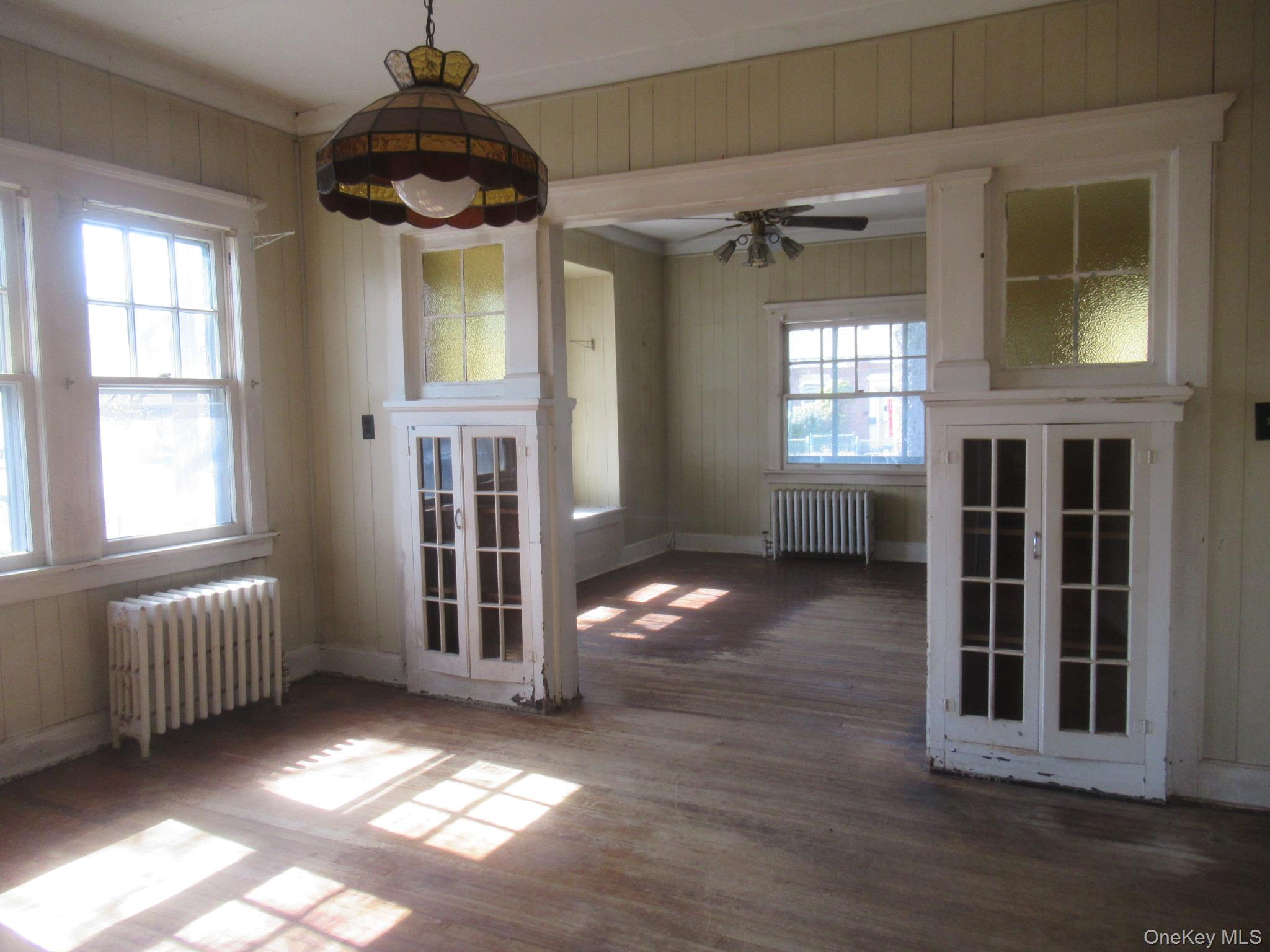 72 Waterstone Road Greenwood Lake, NY 10925 - Photo 7 of 20 Interior space featuring wood-finish flooring, multiple windows, built-in cabinetry with glass panel doors, and a decorative overhead light fixture
