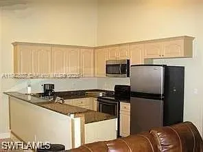 a kitchen with stainless steel appliances granite countertop a refrigerator a sink and white cabinets