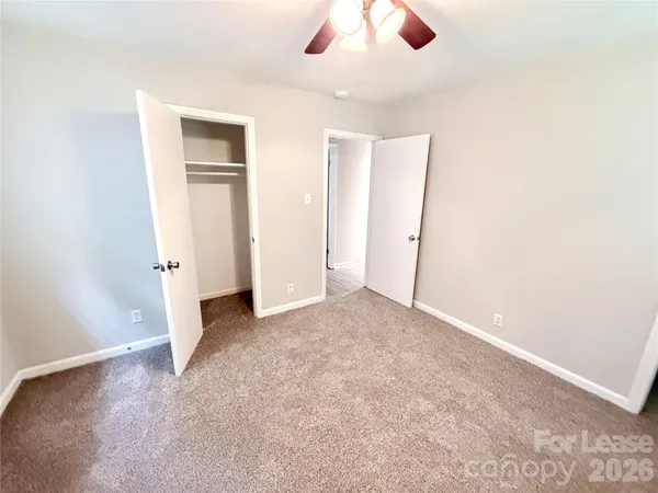 an empty room with closet and a chandelier fan