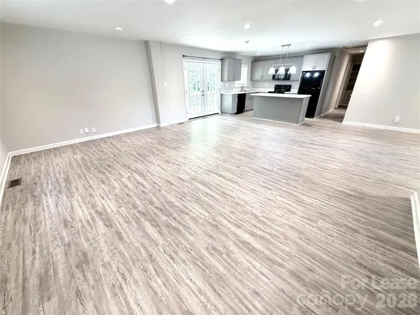 a view of kitchen with kitchen island wooden floors and stainless steel appliances