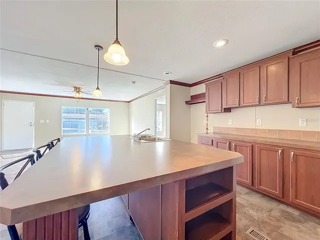 a large kitchen with stainless steel appliances a large counter top a sink a stove and a refrigerator