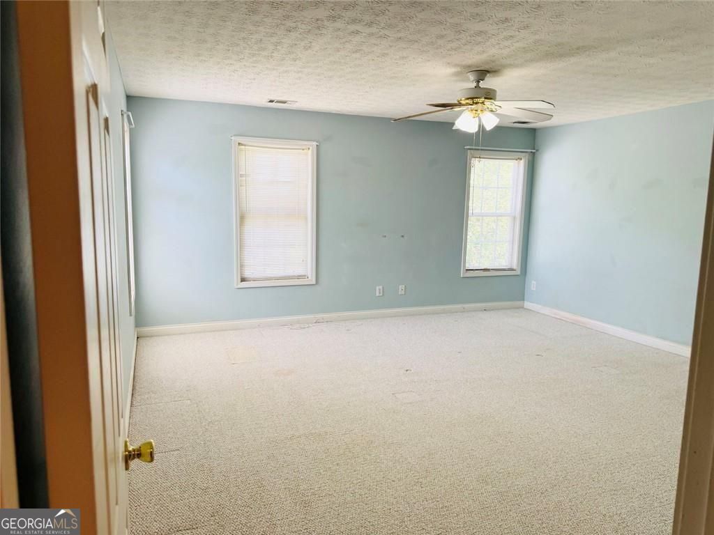 543 Saddle Ridge Drive Bethlehem, GA 30620 - Photo 19 of 36 en empty room with windows and chandelier fan