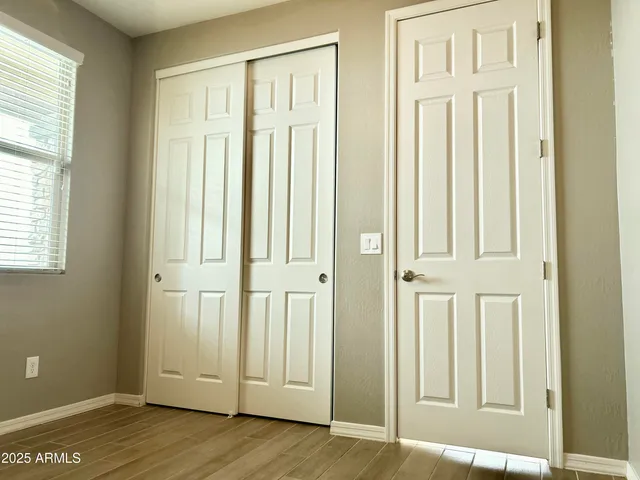 an empty room with wooden floor door and windows