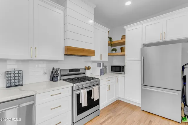 a kitchen with stainless steel appliances white cabinets and a stove top oven