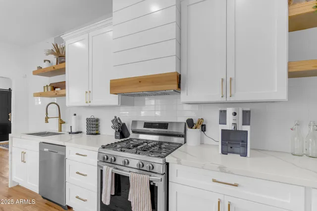 a kitchen with stainless steel appliances granite countertop white cabinets and a stove top oven