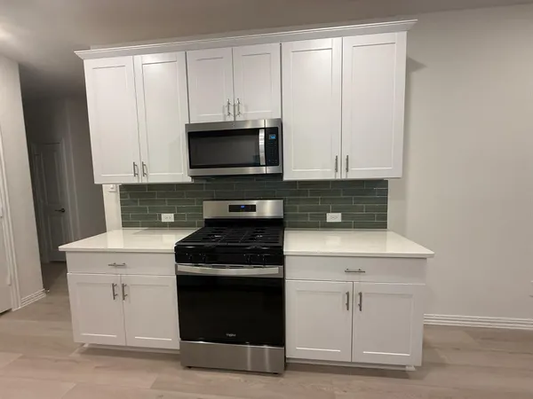 a kitchen with white cabinets and black appliances