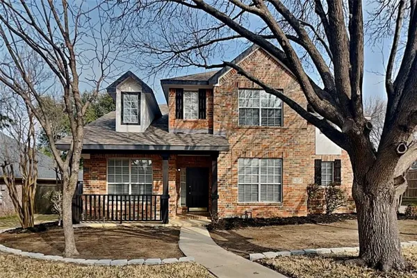a front view of a house with a tree
