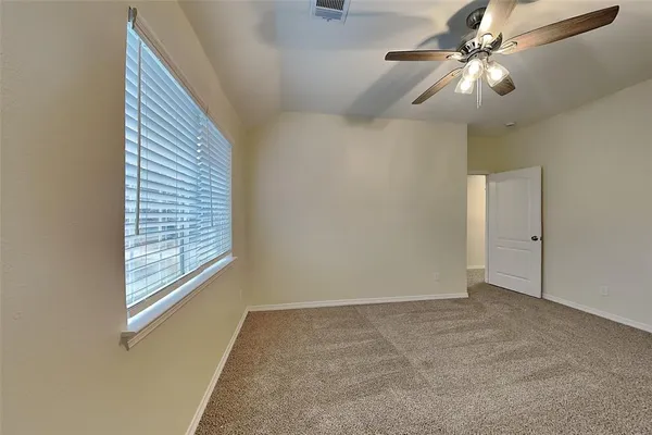 an empty room with windows and fan
