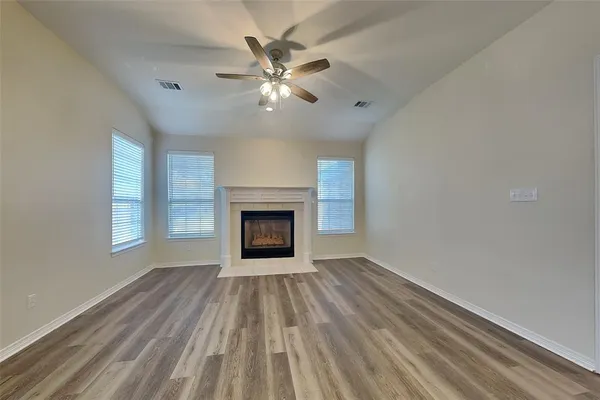 an empty room with windows fireplace and fan