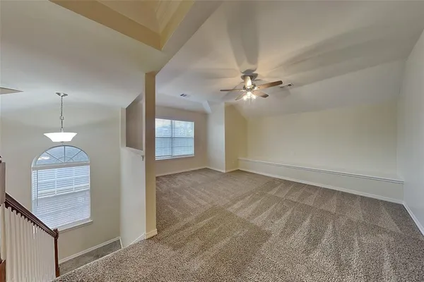 a view of an empty room with a chandelier fan